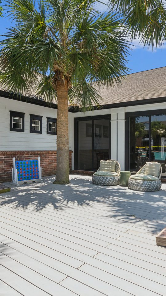 a deck with palm trees and a white fence at The  Boulevard at Deer Park