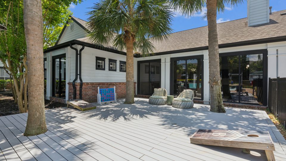 a deck with palm trees and a white fence at The Boulevard at Deer Park