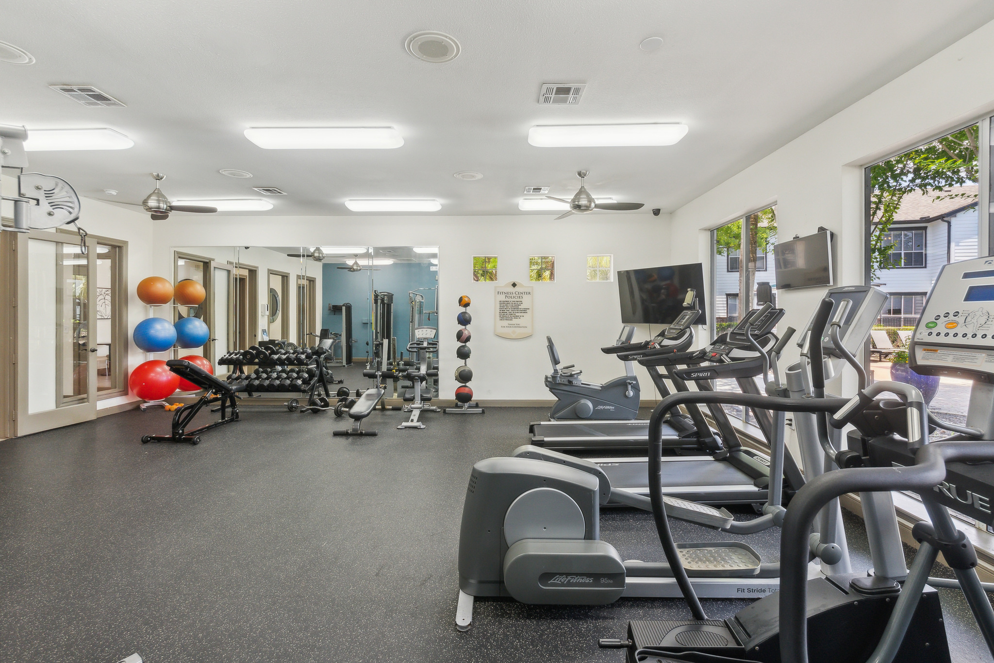 a gym room with treadmills, exercise equipment and a television at The  Boulevard at Deer Park